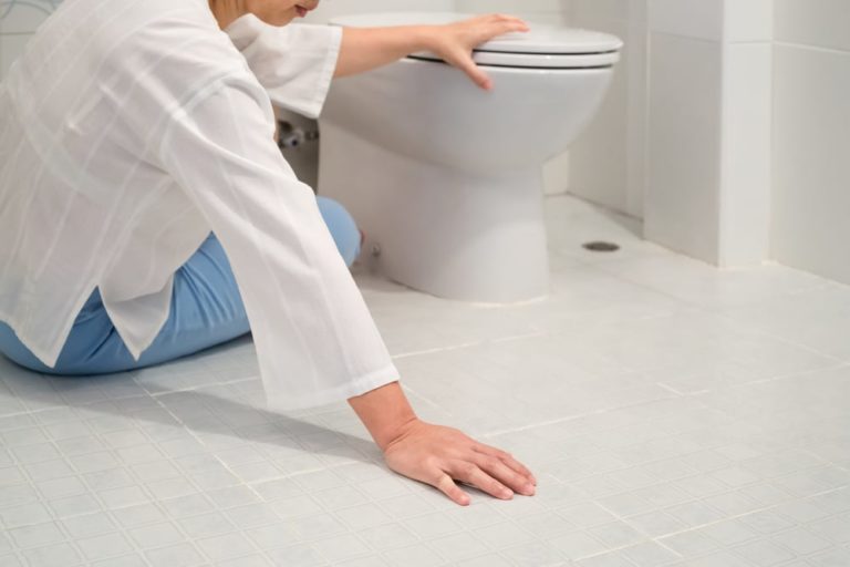Woman holding on to toilet after fall in bathroom