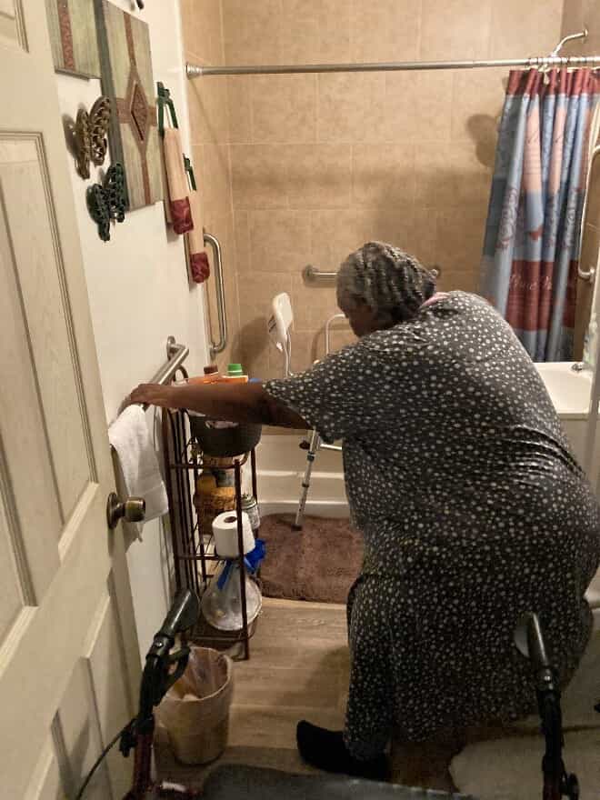 Lady using bathroom grab bar for balance support.